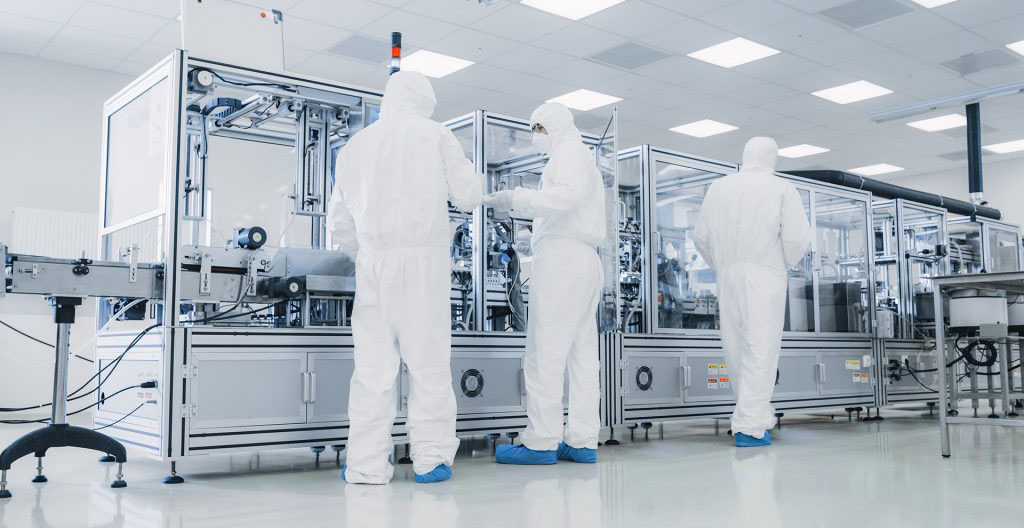 Vue intérieure d'une salle blanche ISO 7 avec techniciens en tenue complète réalisant un assemblage de composants de précision